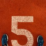 Runner's feet on track lane 5 at the finish line, symbolizing completion and success.